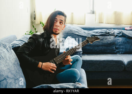 Young guitarist learning to play the guitar in his living room. Stock Photo