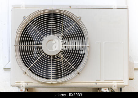 Condenser air conditioner compressor unit on concrete wall. Stock Photo
