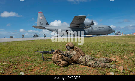 A 736th Security Forces member assigned to Andersen Air Force Base, Guam provides security as members prepare to exit a U.S. C-130 Hercules to set-up a base of operations during the Agile Combat Employment exercise at Andersen AFB, Guam March 6. The exercise was in support of the Air Force’s developing ACE concept of operations capability. (U.S. Air Force photo by Master Sgt. JT May III) Stock Photo