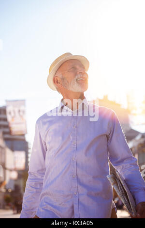 Happy Senior tourist man with suitcase in city. Stock Photo