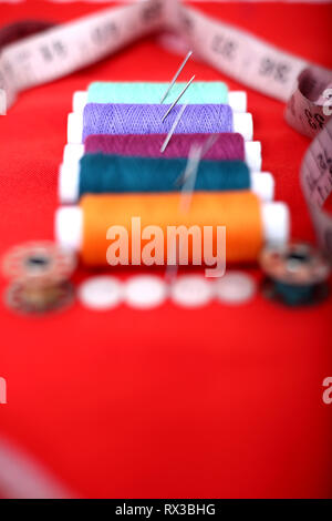 Picture of threads, needles, bobbin and button. Isolated on the red background. Stock Photo