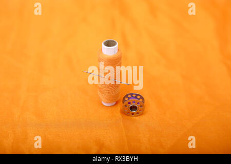 Picture of bobbins and sewing thread with needle . Isolated on the yellow background. Stock Photo