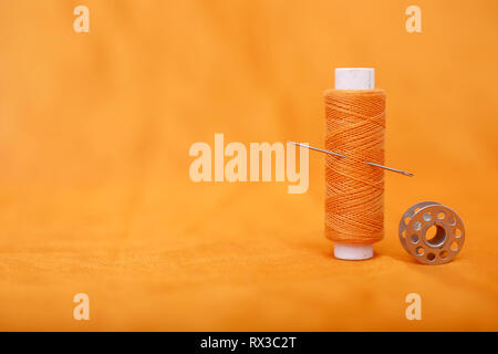 Picture of bobbins and thread with needle . Isolated on the yellow background. Stock Photo