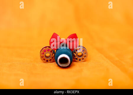 Picture of red bow, threads and bobbin. Isolated on the red background. Stock Photo