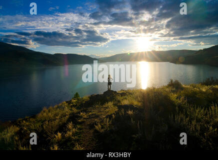 Young girl hiker enjoys summer sunset over Kalamalka Lake near Vernon in the Okanagan region of British Columbia, Canada - MR2 Stock Photo