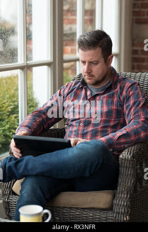 Man in home sunroom uses notebook for telecommute career Stock Photo