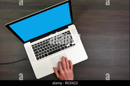 One hand on touchpad from modern laptop on textured wooden table Stock Photo