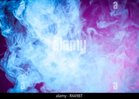 Abstract art colored  blue smoke on pink isolated background. Stop the movement of multicolored smoke on dark background Stock Photo
