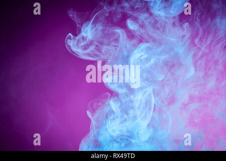 Fog colored with bright blue gel on dark  pink background Stock Photo