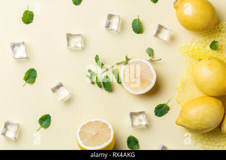 Top view of Lemons with mint leaves and ice cubes over yellow table Stock Photo
