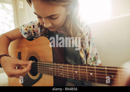 Close up of a teenage girl learning to playing guitar at home. Young girl playing music on guitar. Stock Photo