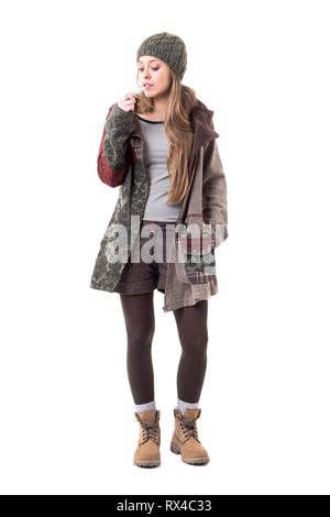 Hipster style woman in warm clothes using electric hearing tobacco hybrid e-cigarette. Full body isolated on white background. Stock Photo
