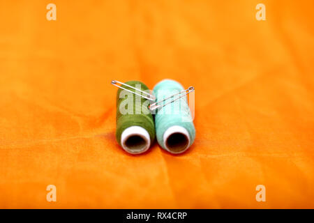 Portrait of safety pin and sewing thread. Isolated on the yellow background. Stock Photo