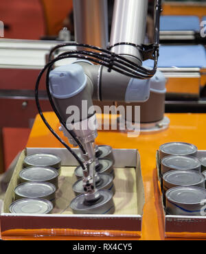 Automation robot lifting food can to conveyor in food industry Stock Photo