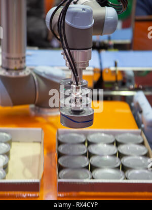 Automation robot lifting food can to conveyor in food industry Stock Photo
