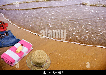 Summer Beach accessories laying on sand in empty sea beach Stock Photo