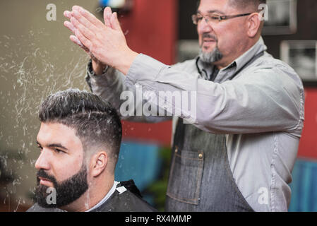 Handsome bearded man, having hair cut at barber shop . Stock Photo