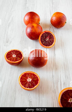 Whole and halved blood oranges on white wooden surface, low angle view. Stock Photo