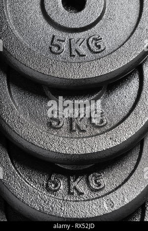 Stack of 5kg barbell / dumbbell weight plates inside a weightlifting gym Stock Photo