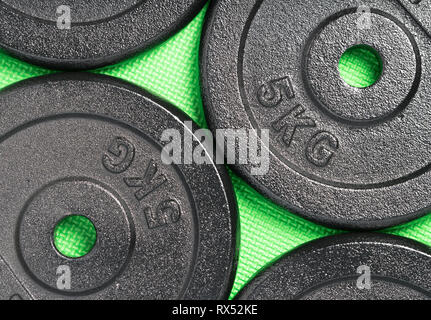 Weight plates on a colourful green floor inside a weight training gym / fitness studio Stock Photo