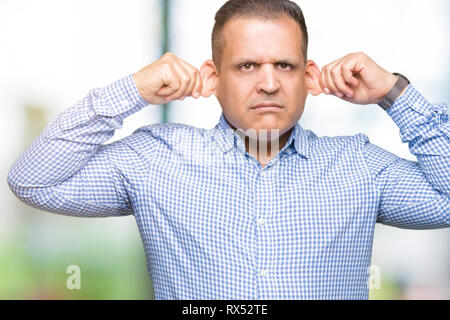 Middle age arab business man over isolated background Smiling pulling ears with fingers, funny gesture. Audition problem Stock Photo