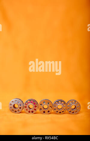 Picture of bobbins with thread. Isolated on the yellow background. Stock Photo