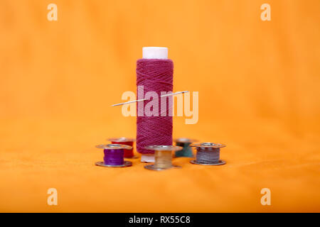 Portrait of one pink thread and bobbins. Isolated on the yellow background. Stock Photo