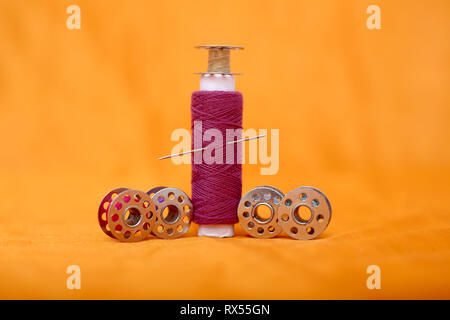 Picture of one pink sewing thread and bobbins. Isolated on the yellow background. Stock Photo