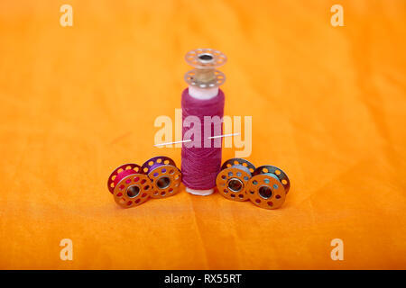 Portrait of one pink sewing thread and bobbins. Isolated on the yellow background. Stock Photo