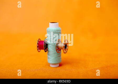 Picture of sewing thread and bobbins. Isolated on the yellow background. Stock Photo