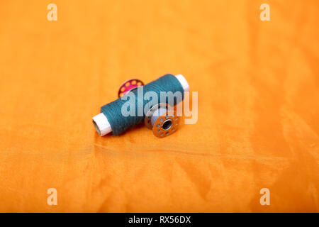 Picture of blue sewing thread and bobbins. Isolated on the yellow background. Stock Photo