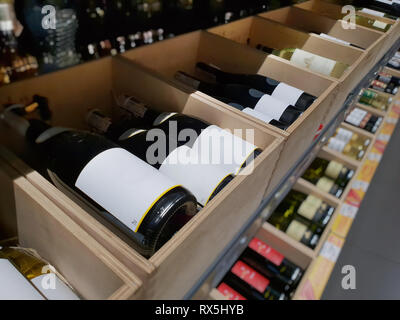 Wine bottles in a wooden crate. The labels of the closest bottles are empty. Stock Photo
