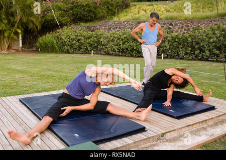 Man teaching women yoga in park Stock Photo