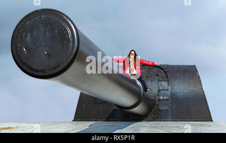 Bateria de Castillitos, Spain - February 28 - 2019: Woman possing at the top of a impressive military cannon for coastal defense Stock Photo