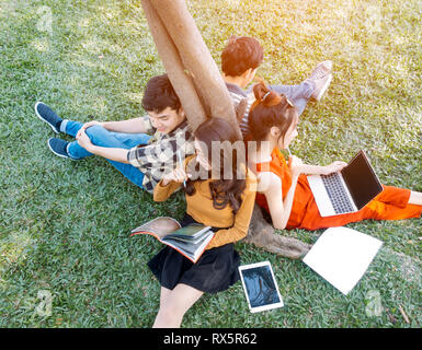 summer, internet, education, campus and teenage concept - group of students or teenagers with laptop and tablet computers hanging out Stock Photo