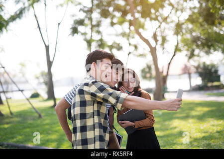 Friends in the park looking using smartphones video call selfie Stock Photo