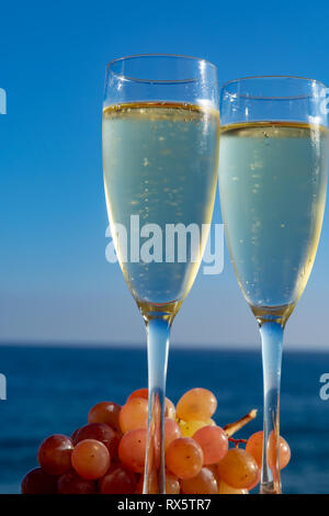 Champagne, prosecco or cava served with pink grape in two glasses on outside terrace with sea view close up Stock Photo