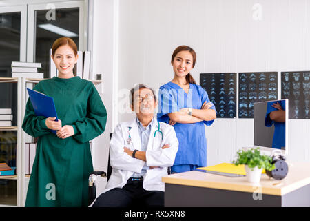 Senior Doctor sitting In Center Of Team with nurse and female doctor Surgeon portrait in office at hospital Stock Photo