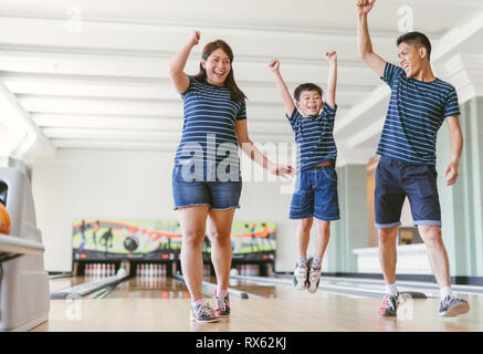 Asian family having fun at bowling club Stock Photo