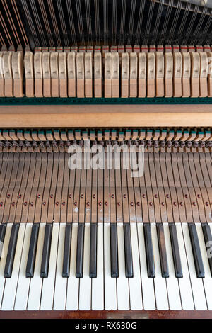 The keyboard and inside of an old upright piano with the casing removed showing the mechanism Stock Photo