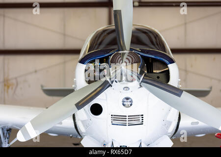 Small white and blue  plane in hangar, small cockpit, private, straight on Stock Photo