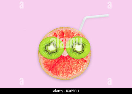 Fruit creative face with slices of grapefruit and kiwi, drinking straw on pink background, fruit juice and summer concept Stock Photo