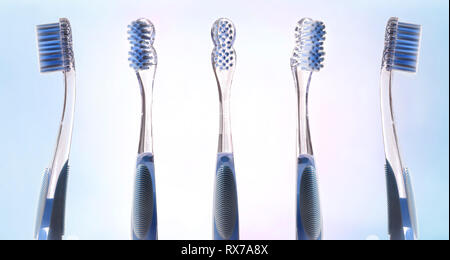 Multiple views of transparent blue toothbrush on pink and blue gradient background. Horizontal composition. Stock Photo
