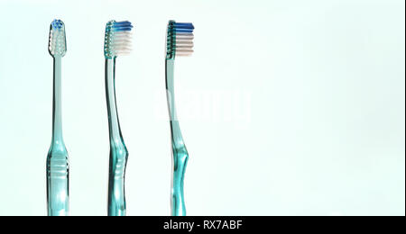 Three views of transparent green toothbrush on green gradient background. Horizontal composition. Stock Photo