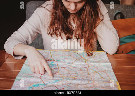 Young woman red head girl traveller reading looking at paper map in cafe Stock Photo