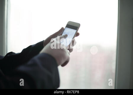 close up. a businessman uses a smartphone while standing near a work table in the office Stock Photo