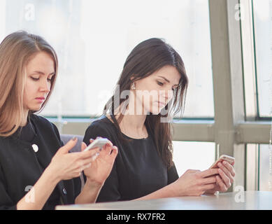 employees using their smartphones sitting at a table in a cafe Stock Photo
