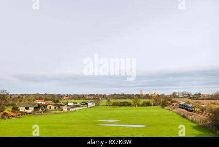 Rural scene with farmhouses, train, fields, and ancient minster on horizxon on bright spring morning in Beverley, Yorkshire, UK. Stock Photo