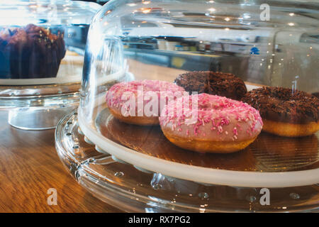 Colorful doughnuts in a glass display container on a shop counter Stock Photo
