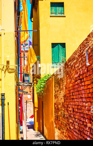 Narrow side street between old yellow houses in Burano, Venice, Italy Stock Photo